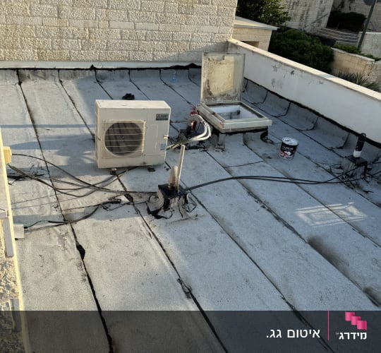 גג עם חומרי איטום, פתח גישה ודלי צבע.